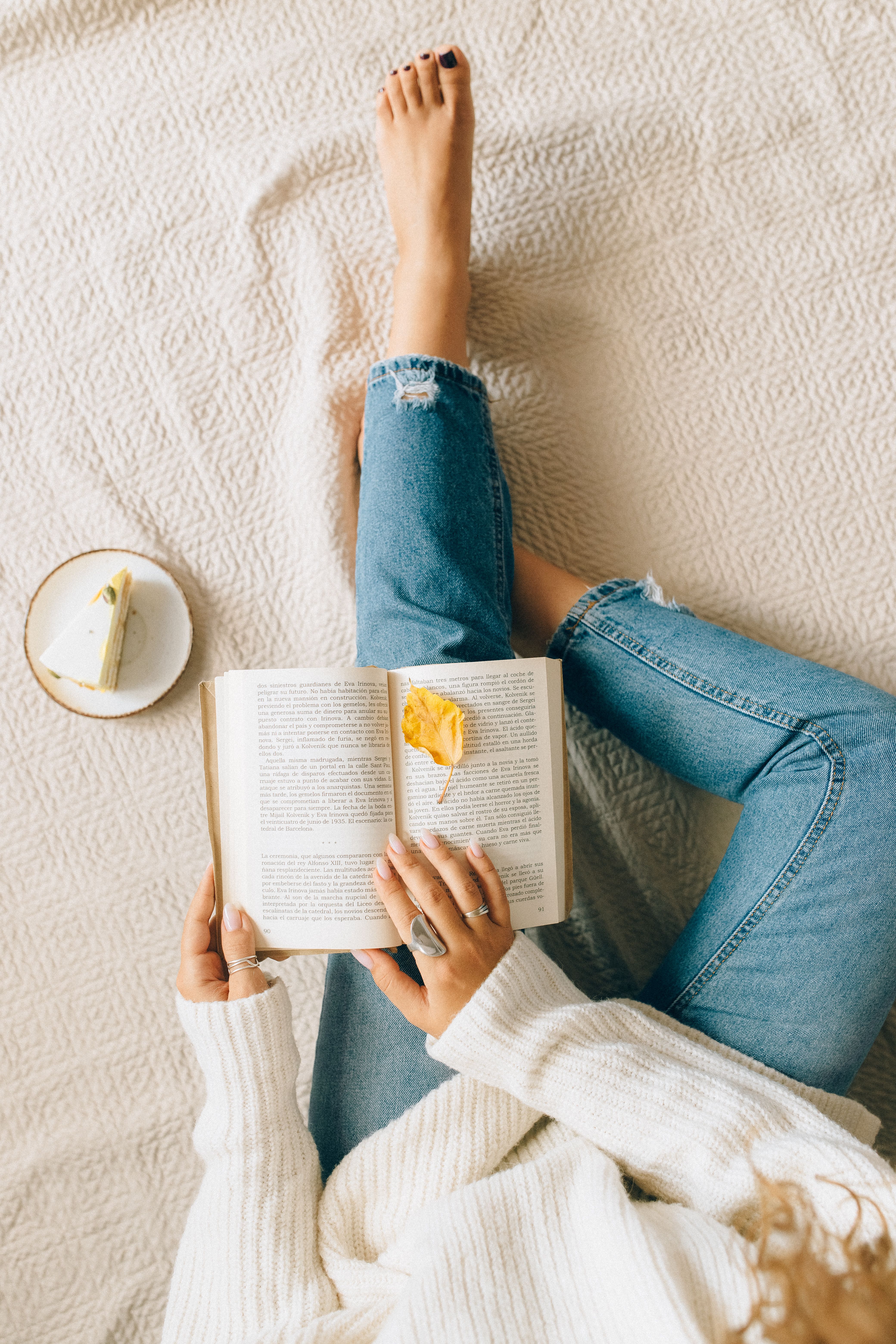 Mujer descansando mientras lee un libro en un ambiente acogedor